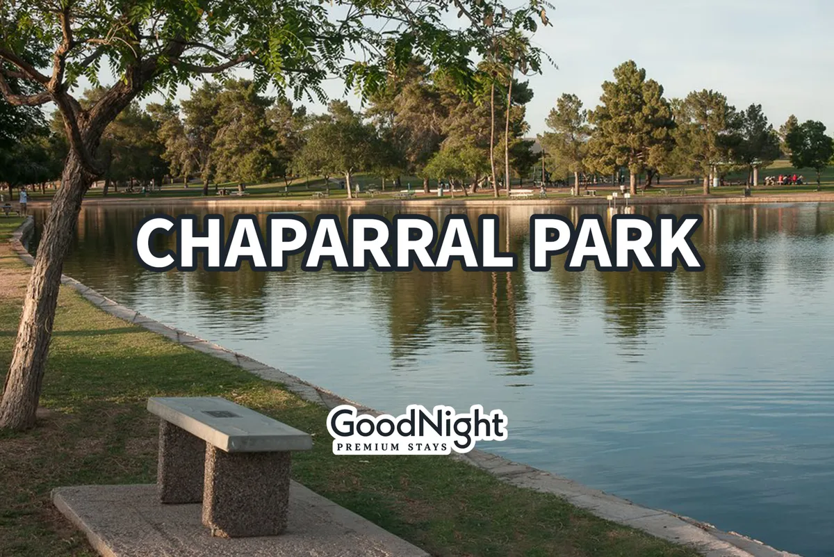 A tranquil lakeside park scene with trees, a bench overlooking the water, and people enjoying the outdoors in the background. The mood is relaxed and invites families to nature walks, picnics, or bird watching.