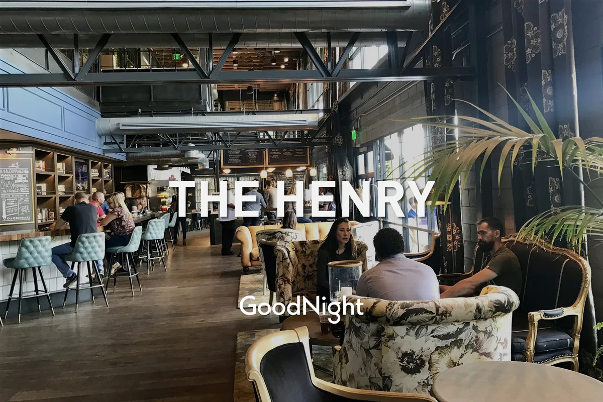 A modern interior bar area with stylish seating arrangements, decorative plants, and patrons enjoying drinks and conversation in a lively, social atmosphere.