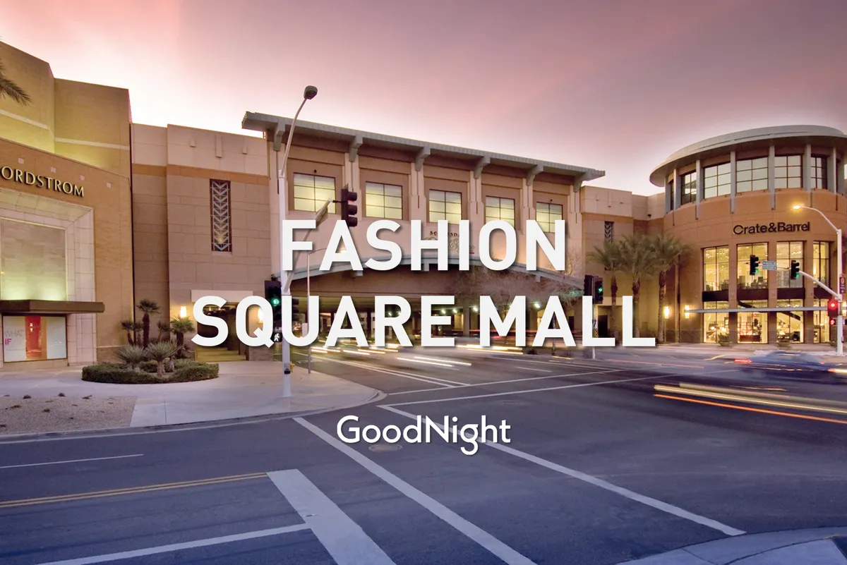 A view of the lively Nordstrom and Crate & Barrel storefronts anchored by palm trees and city traffic, capturing the dynamic and walkable downtown Scottsdale environment. The area buzzes with activity, shopping, and dining opportunities, reflecting the urban energy at the doorstep.
