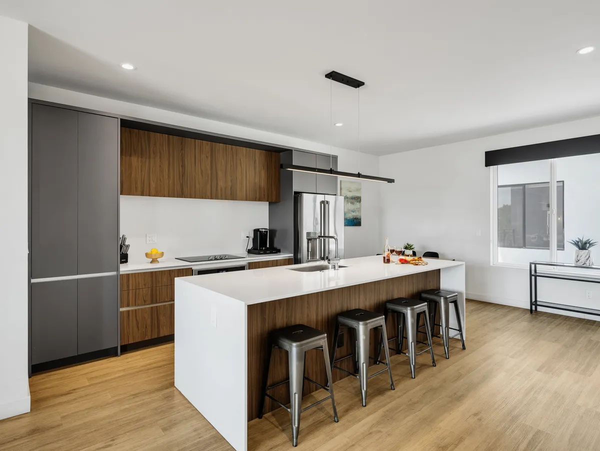 A sleek, modern kitchen with a central island, stainless steel appliances, and bar stools. The setup invites conversation around the island and showcases the premium appliances and functional layout ideal for group cooking or happy hour.