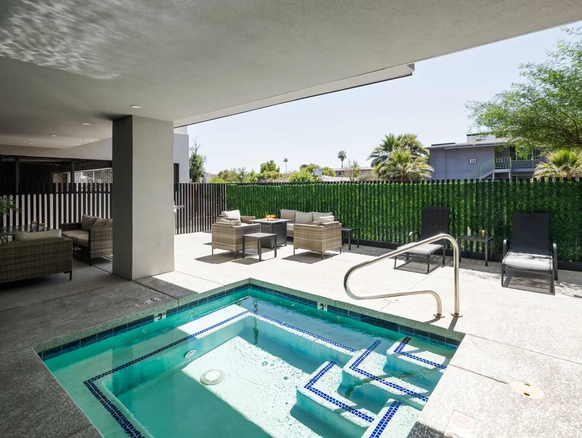 An inviting outdoor area centered around a bubbling jacuzzi, complemented by surrounding lounge chairs and lush greenery. The space is designed for relaxation and socializing, with a tranquil mood suitable for both daytime sunbathing and evening gatherings under the stars.