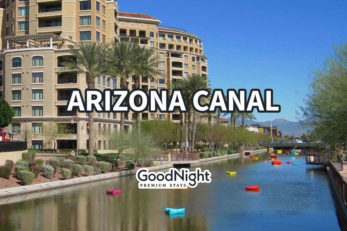 A serene view of the Arizona Canal lined with palm trees, colorful boats, and luxury apartment buildings, suggesting a blend of recreation, relaxation, and upscale living in a scenic setting just steps from the property.